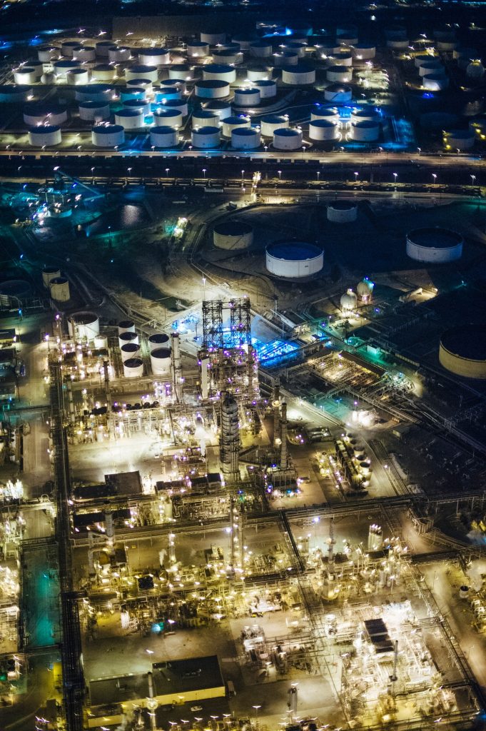 Aerial view of oil refinery and storage tanks illuminated at night, Los Angeles, California, USA